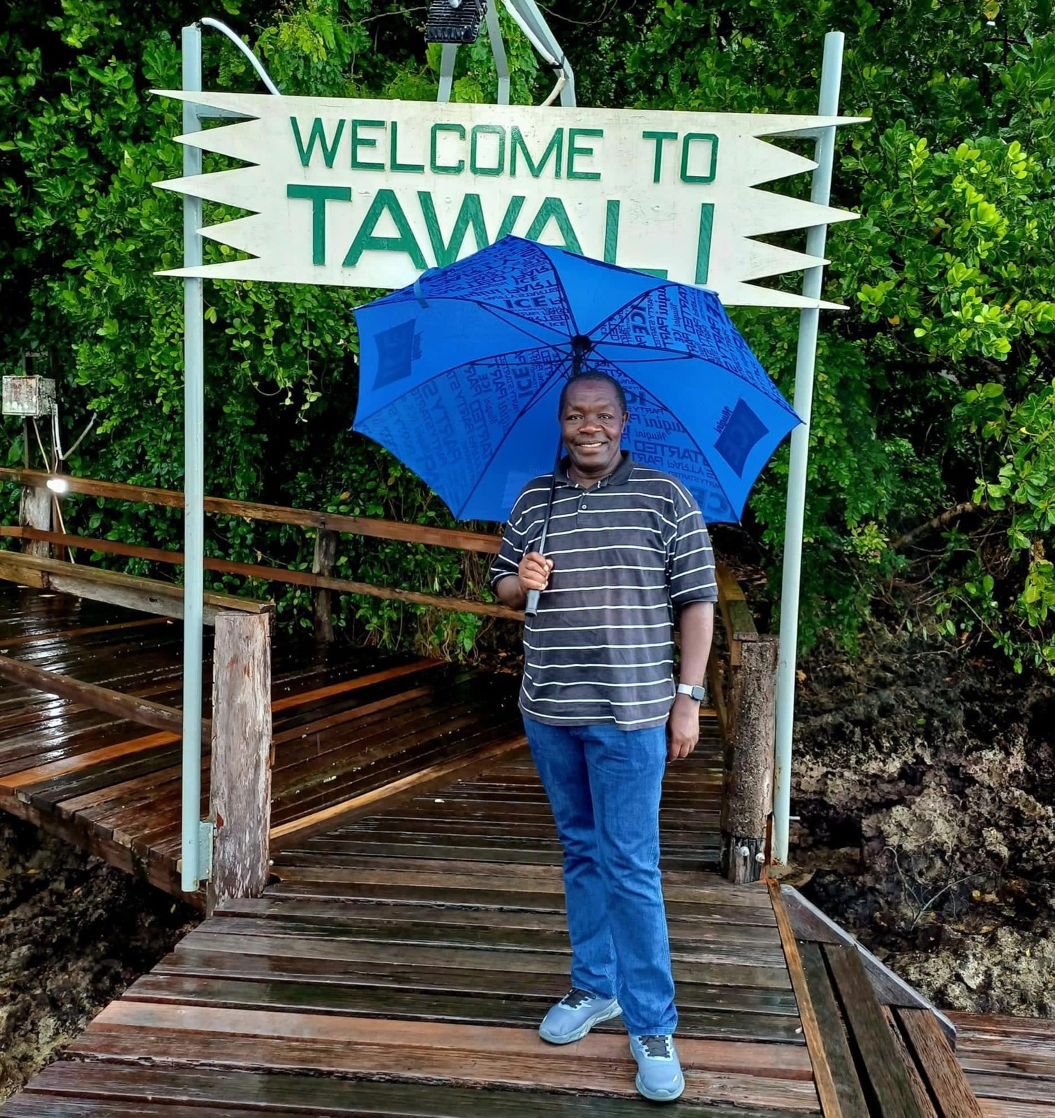 A visitor beneath the Tawali welcome sign, from VilLink’s Discover PNG gallery.